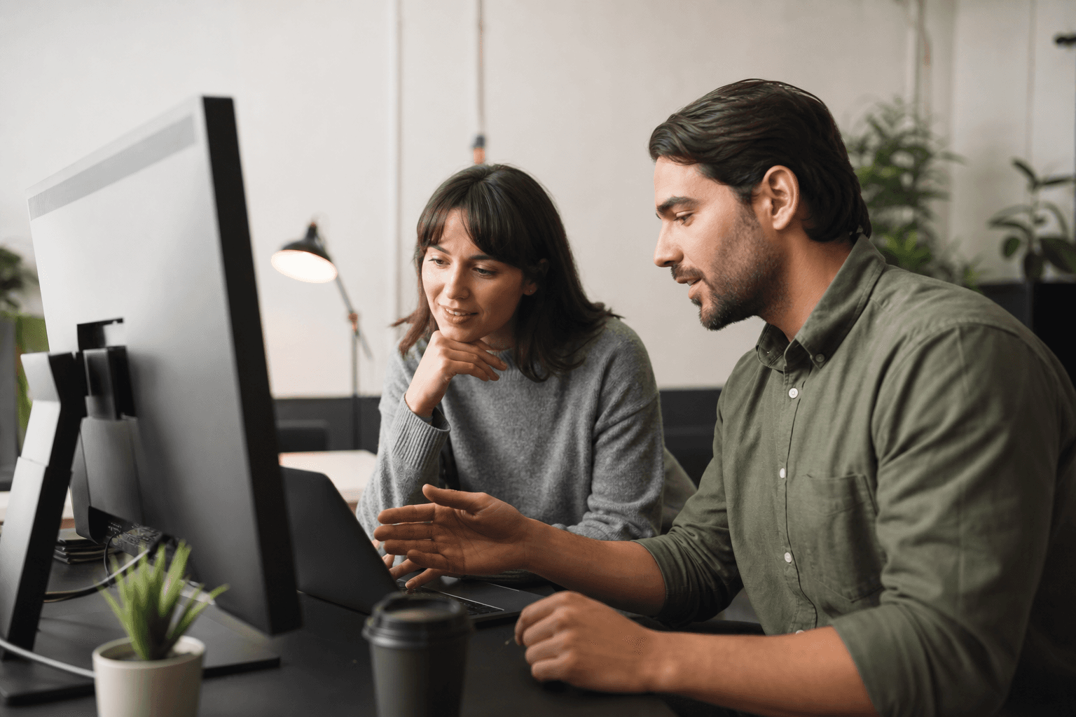 Designer and developer reviewing a live website together on a wide monitor in a bright office