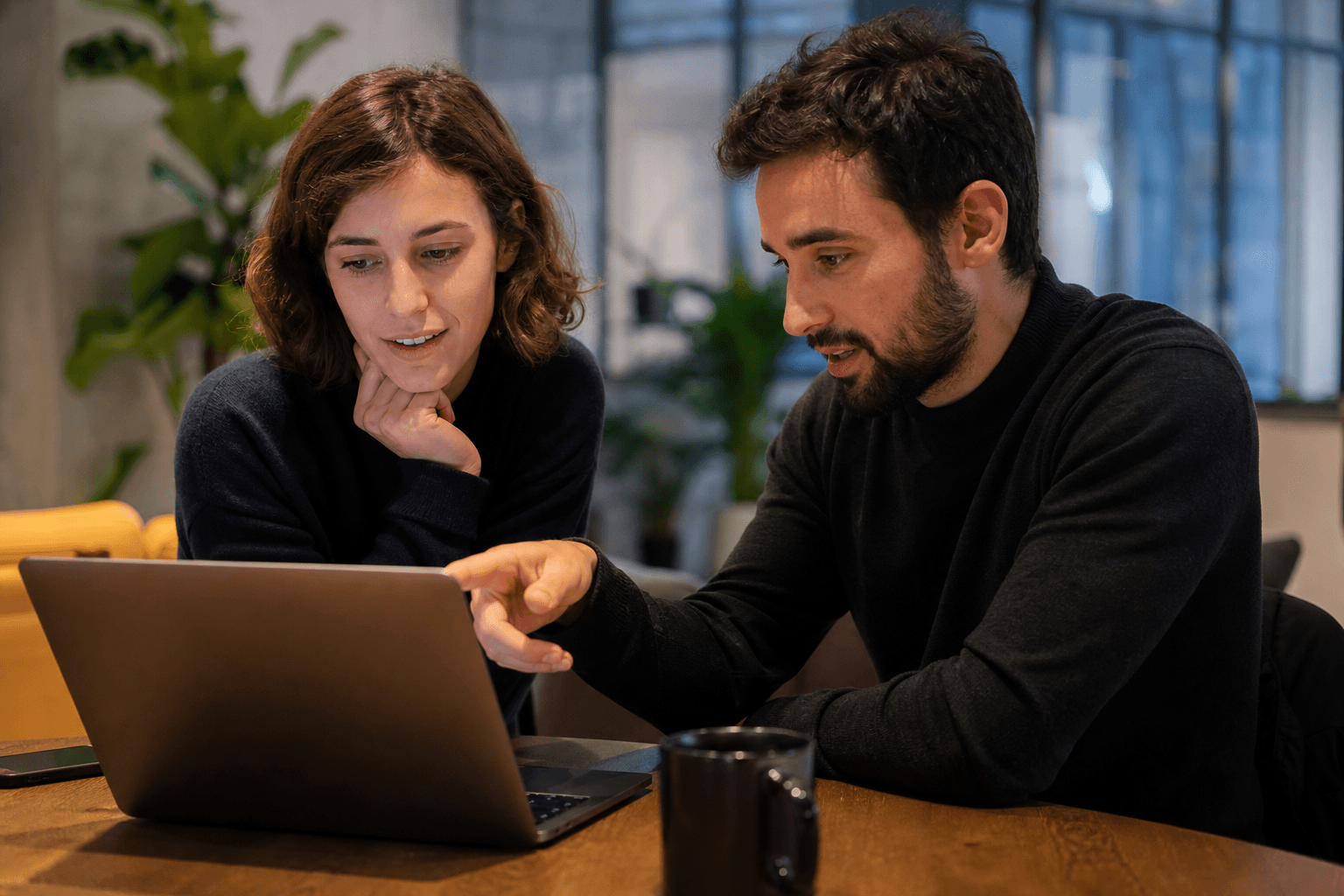 Product team gathered around a monitor reviewing a live webpage with sticky annotations